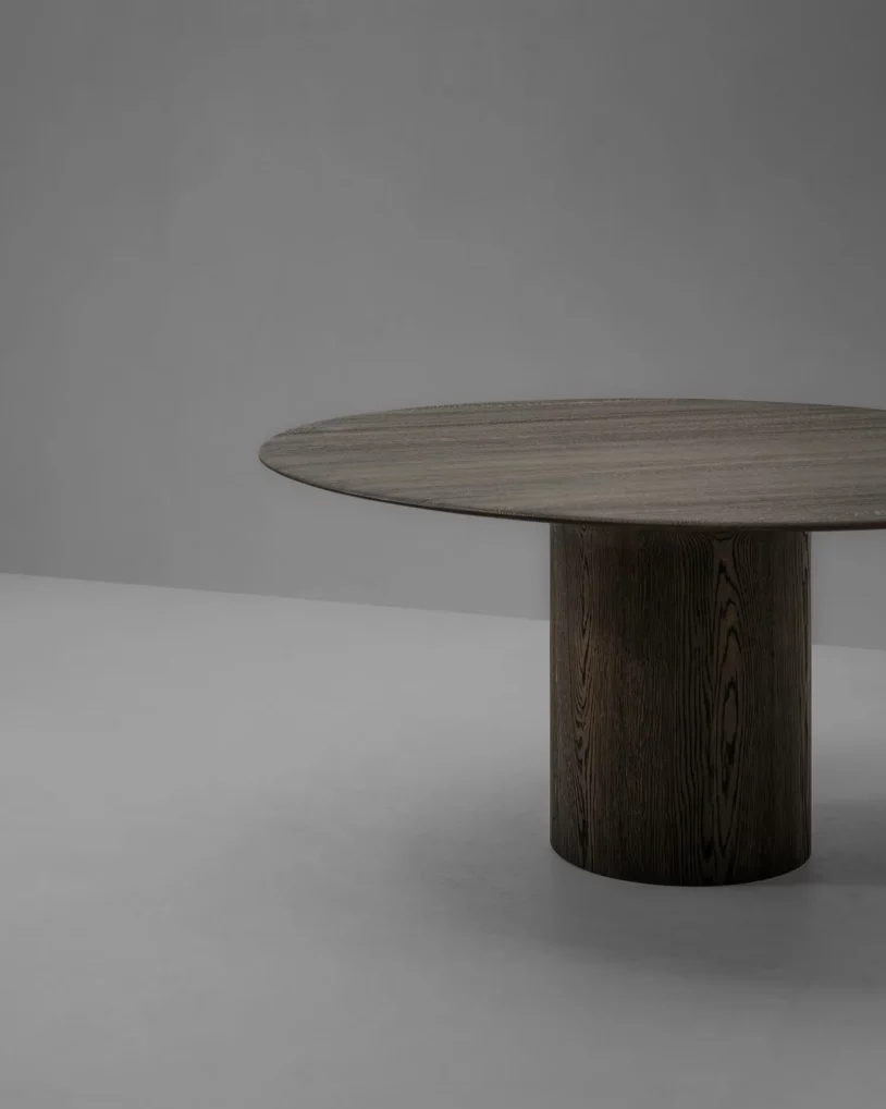 Anvil Dining Table Round Van Rossum, ontwerp Pieter Maes, massief houten eettafel in eiken of walnoot met rond blad en sculpturale basis, verkrijgbaar bij Nuances Leuven